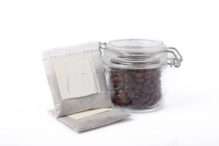 Foto de Bolsa de goteo de café fresco con granos de café aislados sobre fondo blanco.Café molido para preparar en una taza - Imagen libre de derechos