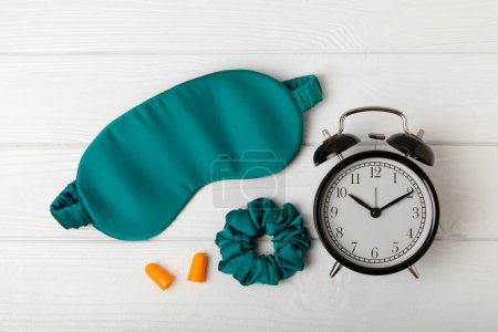 Photo for Sleep mask, alarm clock, earplugs and sleeping pills on a white texture background.Top view.FLETLEY. The concept of restful and sound sleep. Insomnia. - Royalty Free Image