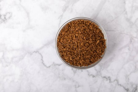 Photo for Instant coffee in a glass bowl. Coffee in granules on a white marble background.Energy hot drink. Place for text. Place for copy. Cheerful morning concept. - Royalty Free Image