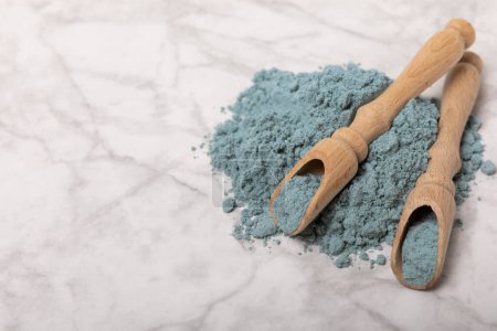 Téléchargez les photos : Blue spirulina powder in wooden spoons on a marble background. Natural superfood, vegan, healthy food supplement. Phycocyanin extract. Antioxidant. Place for text. Copy space. - en image libre de droit