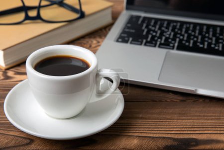 Foto de Desk with laptop, glasses, notepads and a cup of coffee on the desktop.Workspace with copy space. Mocap. Business concept. Place for text. Flat lay - Imagen libre de derechos