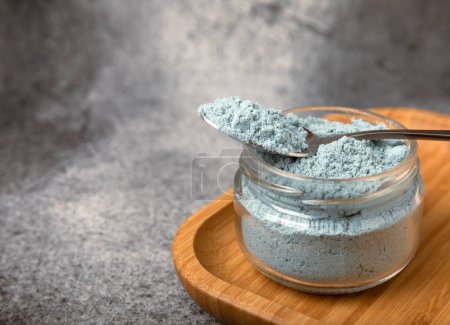 Téléchargez les photos : Blue spirulina powder in a bowl on a black textured surface. Natural vegan superfood. Healthy food supplement. Phycocyanin extract. Place for text. Place for a copy. - en image libre de droit