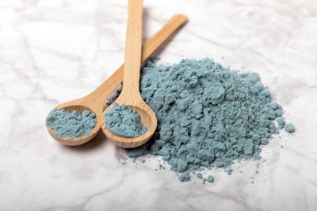Téléchargez les photos : Blue spirulina powder in bowls and spoons on a marble table. Natural vegan superfood. Healthy food supplement. Phycocyanin extract. Place for text. Place for a copy. - en image libre de droit