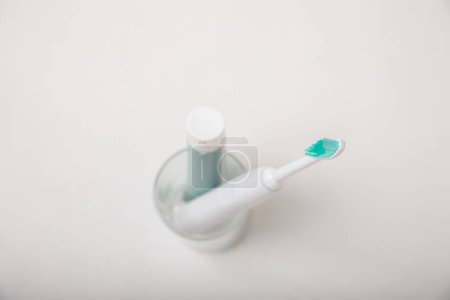 Photo for Electronic ultrasonic toothbrush and toothpaste on texture background. Items for dental care and caries prevention in the bathroom. Dentistry concept. Copy space. - Royalty Free Image