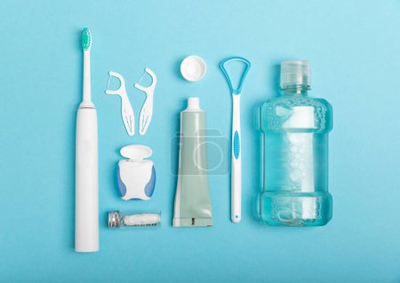 Photo for Toothbrush,electric toothbrush,tongue cleaner, floss, toothpaste tube and mouthwash on blue background with copy space. Flat lay. Dental hygiene. Oral care kit. Dentist concept.Dental care. - Royalty Free Image