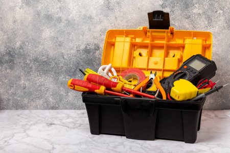 Electrician tools on white marble background.Multimeter,construction tape,electrical tape, screwdrivers,pliers,an automatic insulation stripper,socket and LED lamp.Flatley.electrician concept.Toolbox.