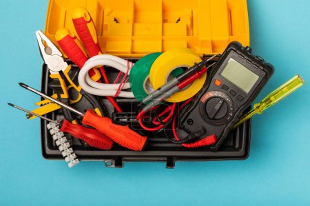 Photo for Electrician equipment on blue background with copy space.Top view.Electrician tool set.Multimeter, tester,screwdrivers,cutters,duct tape,lamps,tape measure and wires.Flet lay. - Royalty Free Image
