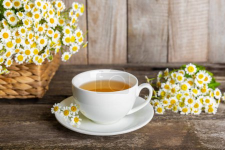 Herbal chamomile tea in a cup on a brown wooden table with honey, lemon and chamomile bouquet. Close-up. Copy space. healthy herbal drinks, immunity tea. Natural healer concept.Place for text.