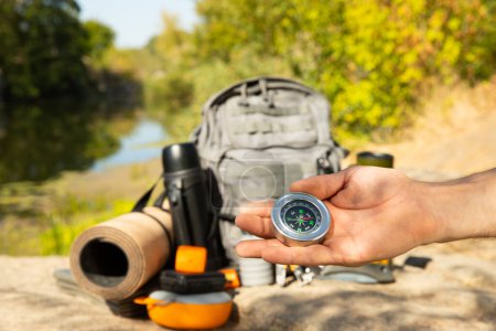 Photo for Man traveler holding a compass in her hand in the summer mountains at dawn.Tourist in the mountains with a compass against the backdrop of nature.The concept of tourism,sports and active recreation - Royalty Free Image