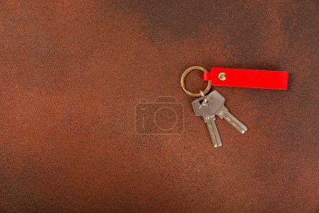 Téléchargez les photos : Porte-clés en cuir avec un porte-clés sur fond texturé. Concepts pour l'immobilier et le déménagement ou la location de biens. Acheter une propriété. Porte-clés maquillage.Espace de copie. - en image libre de droit