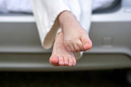 Photo for Travel. A child in a car. Picnic in the car. Feet of a child in white jeans sitting in the trunk of a silver grey car - Royalty Free Image