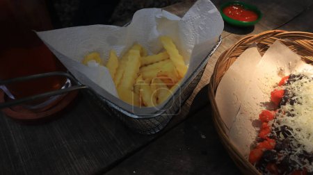 Téléchargez les photos : Snacks sont servis sur la table, pommes de terre et bananes frites saupoudrées de fromage - en image libre de droit