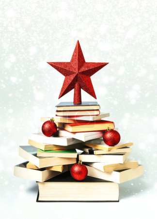 Photo for Christmas concept background. Books in the form of a christmas tree with christmas balls and red star over christmas lights and snowflakes - Royalty Free Image