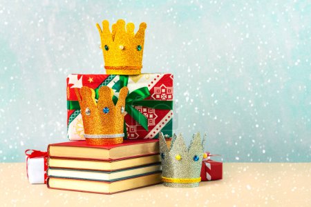 Téléchargez les photos : Trois couronnes des trois sages avec des livres, des boîtes cadeaux de Noël et des flocons de neige sur fond bleu - en image libre de droit