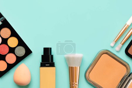 Photo for Top view of makeup brushes, eyeshadow, beauty makeup sponge,foundation and face powder with space for text over blue background. Beauty and makeup concept - Royalty Free Image
