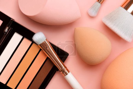 Photo for Top view of eyeshadow, makeup sponges and makeup brushes over pink background. Beauty and makeup concept - Royalty Free Image