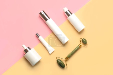 Photo for Set of cosmetics and jade massanger roller for skin care over yellow and pink background. Skin care products concept - Royalty Free Image