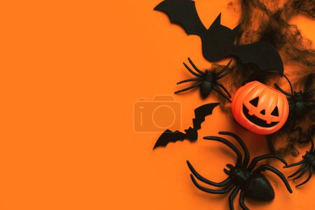 Fondo concepto Halloween. Vista superior de la cesta de calabaza, arañas y murciélagos con espacio para texto sobre fondo naranja. Halloween concepto de decoración de fiesta