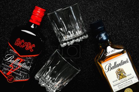 Foto de La botella de whisky escocés de Ballantine edición especial de la icónica banda de rock ACDC y el whisky escocés mezclado de Ballantine con dos vasos de whisky sobre fondo negro. Editorial ilustrativo - Imagen libre de derechos