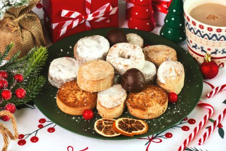 Top view of mantecados and polvorones with christmas ornaments on a plate on a christmas tablecloth. Assortment of christmas sweets typical in Spain