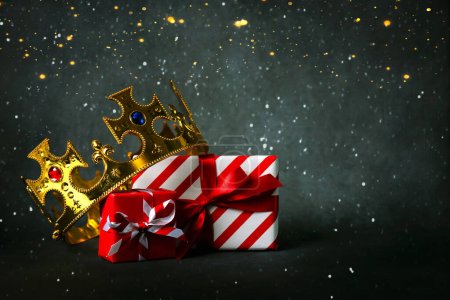 Krone der drei Weisen mit Weihnachtsgeschenkschachteln und Weihnachtsbeleuchtung vor grauem Hintergrund. Konzept für den Dia de Reyes Magos Tag. Die drei Weisen