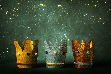 Photo for Three crowns of the three wise men and christmas lights over gray background. Concept for Reyes Magos day. Three Wise Men concept - Royalty Free Image
