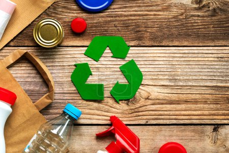 Draufsicht auf das Symbol des Recyclings mit verschiedenen Müllmaterialien auf einem Holztisch mit Platz für Text. Umweltfreundliches Recyclingkonzept