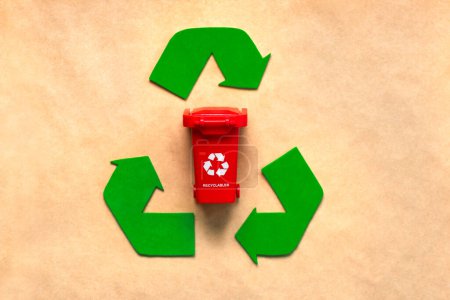 Top view of Symbol of recycling with red recycle bin on recycled paper background. Eco friendly recycling concept