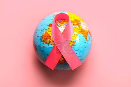 Draufsicht auf das rosafarbene Schleifensymbol des Brustkrebses auf einer Weltkugel auf rosa Hintergrund. Brustkrebs-Aufklärungskonzept