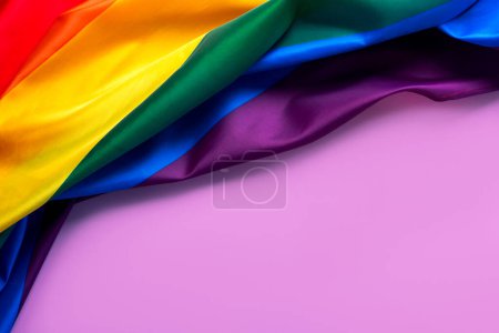 Top view of LGBT Pride Rainbow Flag with copy space for text over purple background. LGBT Pride concept