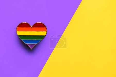 Closeup of LGTBI pin heart shaped with copy space for text over purple and yellow background. LGBT Pride concept