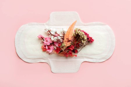 Draufsicht auf Damenbinden und Blumensträuße auf rosa Hintergrund. Konzept der Menstruation
