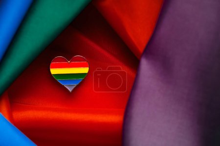 Closeup of LGTBI pin heart shaped on LGBT Pride Rainbow Flag. LGBT Pride concept