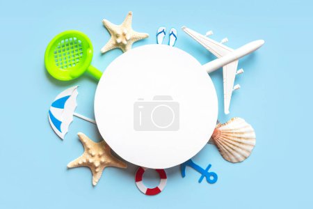 Flat lay composition with starfish, seashells, beach accessories and plane with round blank with copy space for text over blue background