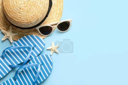 Top view of flip flops,sunglasses,starfish and straw hat with copy space for text over blue background. Summer holiday concept