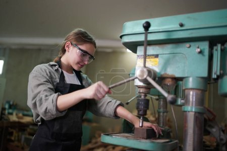 Foto de Pequeño negocio de una mujer joven. Hermosa joven trabajadora en un taller de muebles, midiendo madera. - Imagen libre de derechos