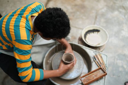 Photo for Young Afro teenager hand potter making clay vase in pottery workshop - Royalty Free Image