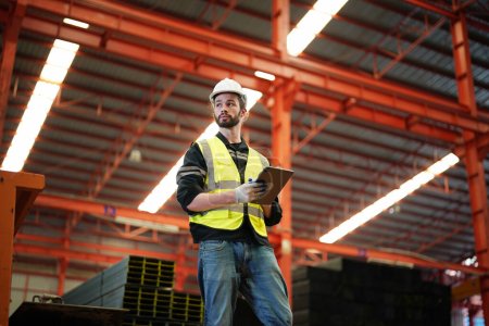 Photo for Male worker in safety vest writing in storehouse - Royalty Free Image