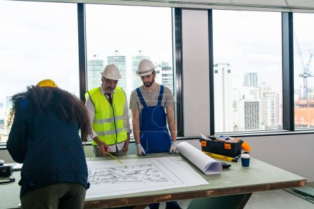 Foto de Ingenieros masculinos de pie en la obra, sosteniendo planos. - Imagen libre de derechos