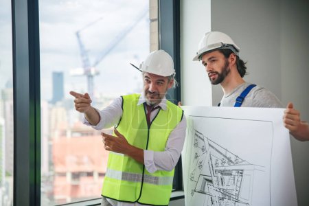 Téléchargez les photos : Ingénieurs debout sur le chantier, tenant des plans. - en image libre de droit
