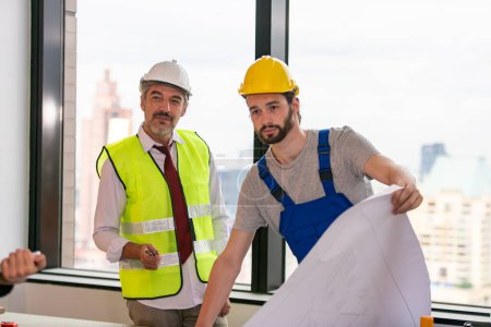 Téléchargez les photos : Ingénieurs debout sur le chantier, tenant des plans. - en image libre de droit