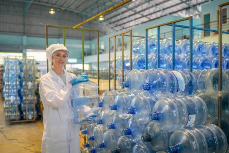 Photo for Woman working at Reverse osmosis system for power plant. RO system for industry, equipment which popular to install with pipe at industrial such chemical, power plant, oil and gas. Young happy female worker in bottling factory checking water bottles - Royalty Free Image