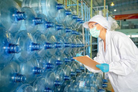 Photo for Woman working at Reverse osmosis system for power plant. RO system for industry, equipment which popular to install with pipe at industrial such chemical, power plant. Young happy female worker in bottling factory checking water bottles - Royalty Free Image