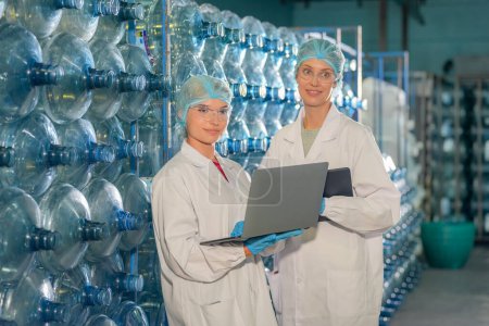 Photo for Women working at Reverse osmosis system for power plant. RO system for industry, equipment which popular to install with pipe at industrial such chemical, power plant, oil and gas. Young female workers in bottling factory checking water bottles - Royalty Free Image