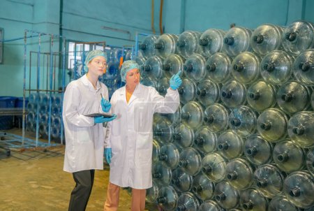Photo for Women working at Reverse osmosis system for power plant. RO system for industry, equipment which popular to install with pipe at industrial such chemical, power plant, oil and gas. Young  female workers in bottling factory checking water bottles - Royalty Free Image