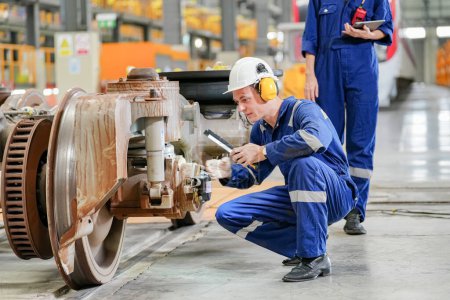 Foto de Ingenieros inspeccionando locomotoras en instalaciones de ingeniería ferroviaria - Imagen libre de derechos