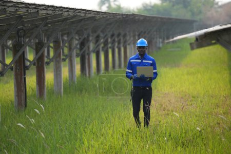 Photo for Electrician engineer with  helmet working at a photovoltaic farm, checking and maintenance equipment with instruments at industry solar power. - Royalty Free Image
