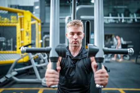Téléchargez les photos : Athlète masculin faisant de l'exercice dans la salle de gym, soulevant des poids, tirant des articulations. - en image libre de droit