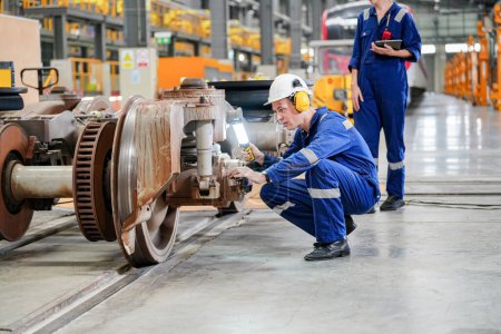 Téléchargez les photos : Ingénieurs inspectant une locomotive dans une installation de génie ferroviaire - en image libre de droit
