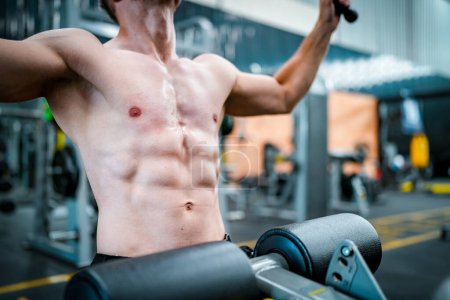 Photo for Male athlete exercising in the gym, lifting weights, pulling joints. - Royalty Free Image